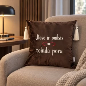 Tamsiai ruda dekoratyvinė pagalvėlė su siuvinėtu užrašu „Bosė ir poilsis = tobula pora“, raudona širdele ir šviesiais kutais