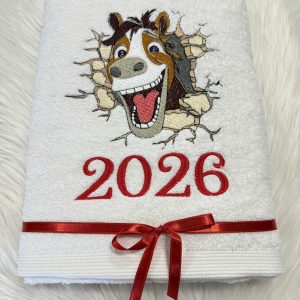 Baltas siuvinėtas rankšluostis su linksmu arklio atvaizdu ir užrašu „2026“, perrištas atlasiniu kaspinėliu