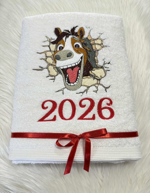 Baltas siuvinėtas rankšluostis su linksmu arklio atvaizdu ir užrašu „2026“, perrištas atlasiniu kaspinėliu
