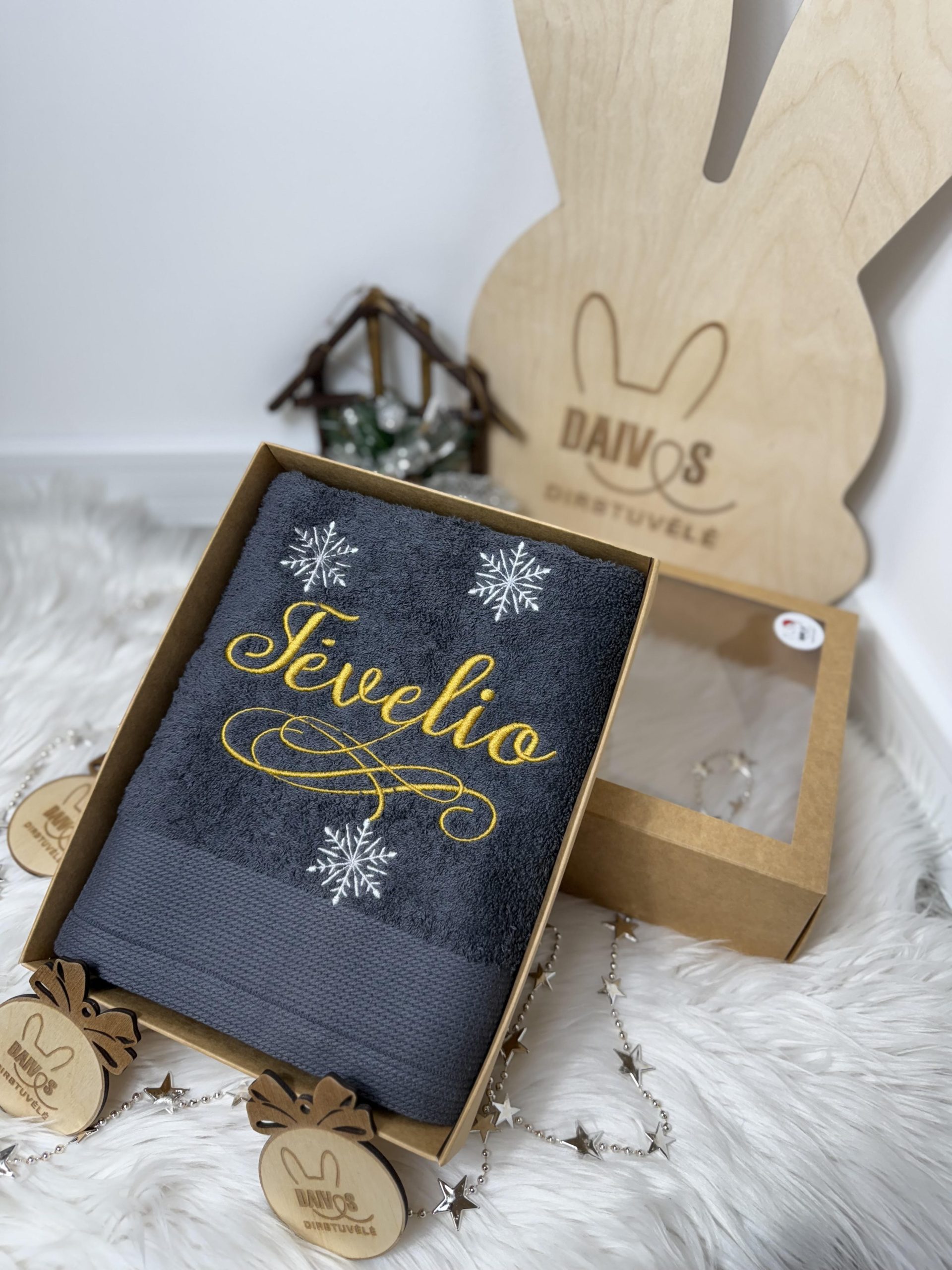 Pilkas siuvinėtas rankšluostis dėžutėje su užrašais „Tėvelio“ papuošta snaigėmis.