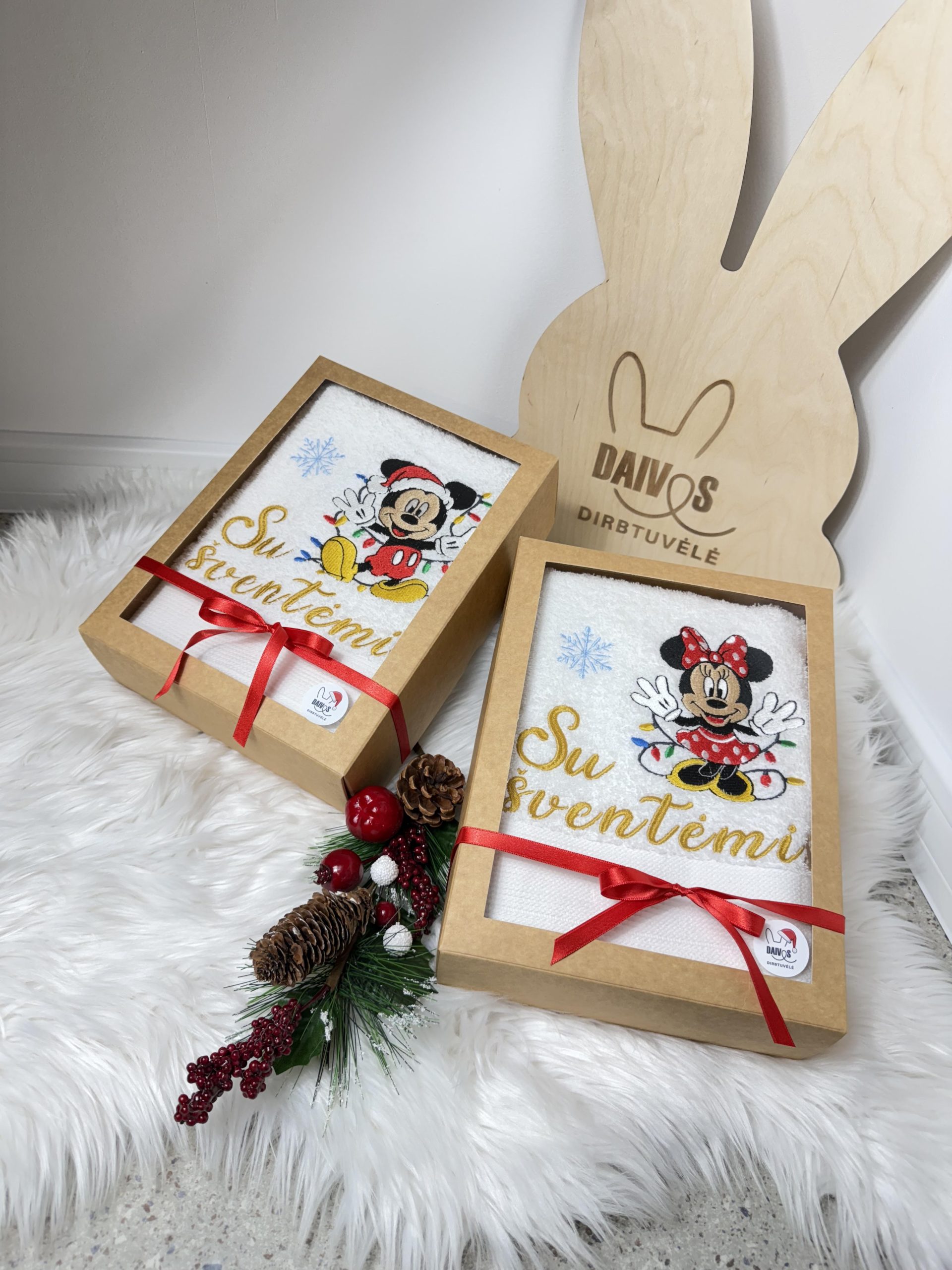 Balti siuvinėti rankšluosčiai su Mikimauzu ir Mine, su užrašu „Su šventėmis“ ir raudonais kaspinais.